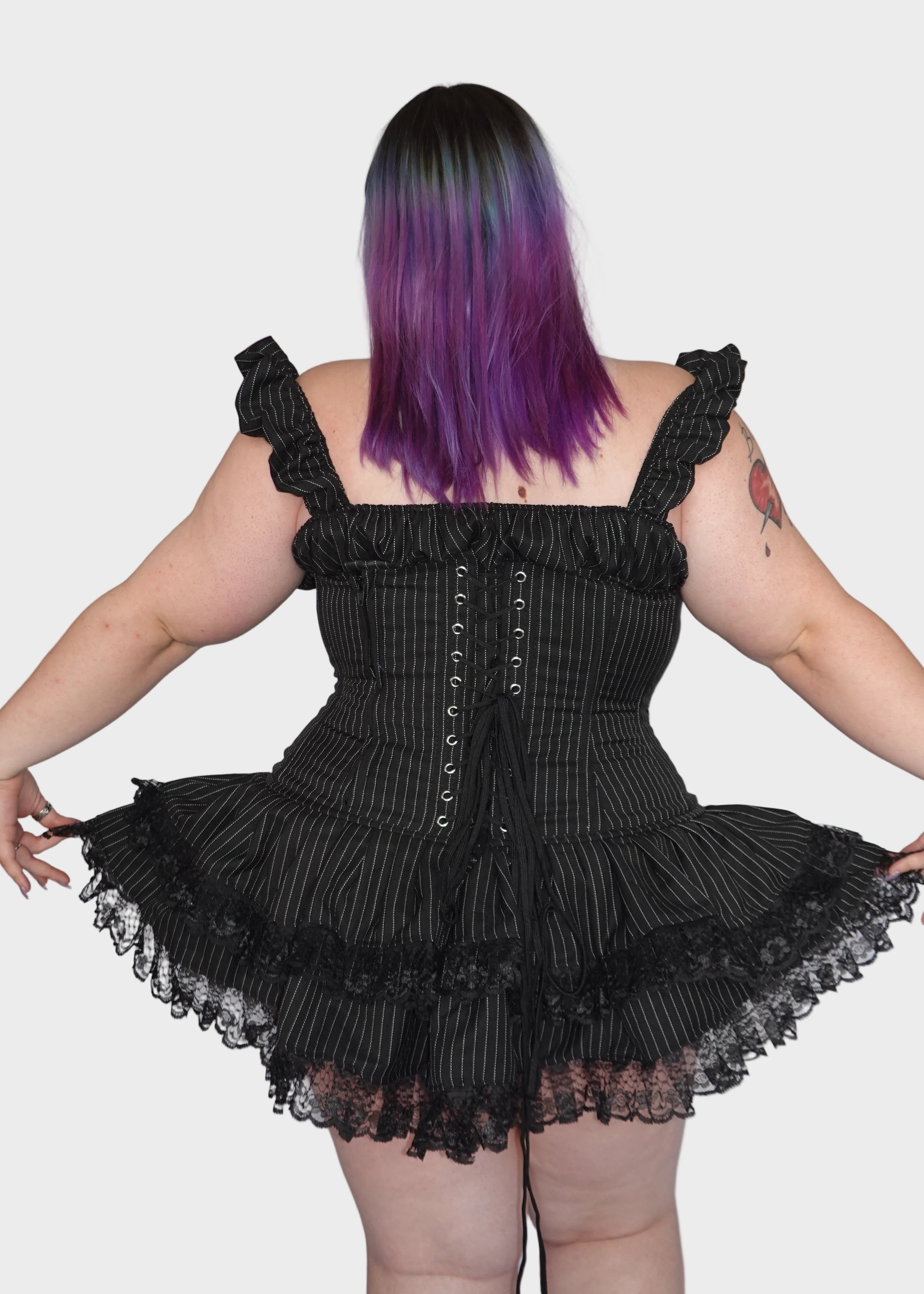 Back view of black pinstripe gothic steel-boned corset mini dress with two tier ruffled lace skirt showing adjustable lace-up back closure on model - Sirena Mini Dress - FM2U Clothing Australia | Gothic Alternative Whimsical Ethical Fashion