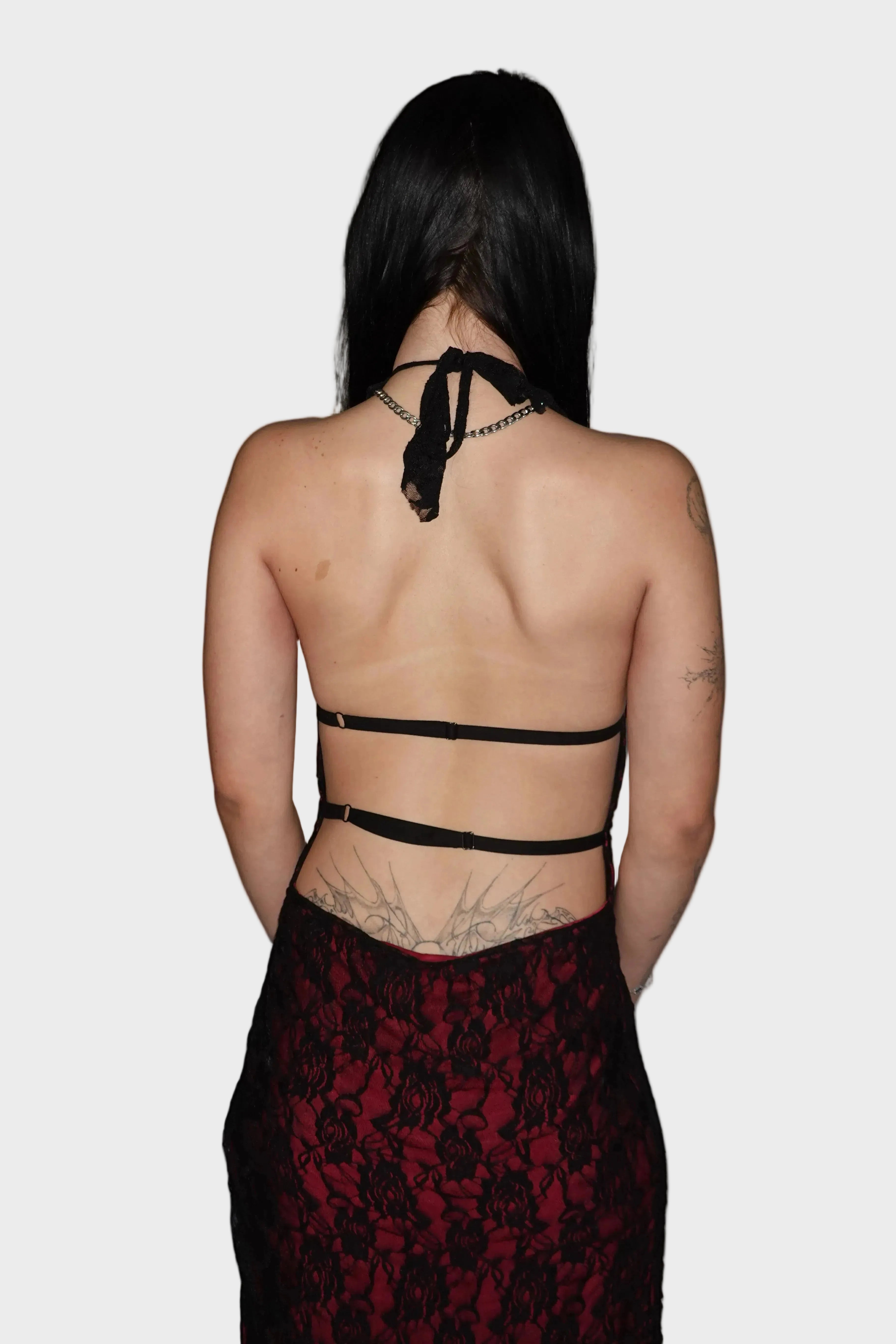 back shot of backless dark red dress with black lace overlay, showcasing adjustable halter neckline and two adjustable back straps to cinch the dress. On model - Elvira Vampiress - FM2U Clothing Australia | Gothic Alternative Whimsical Ethical Fashion