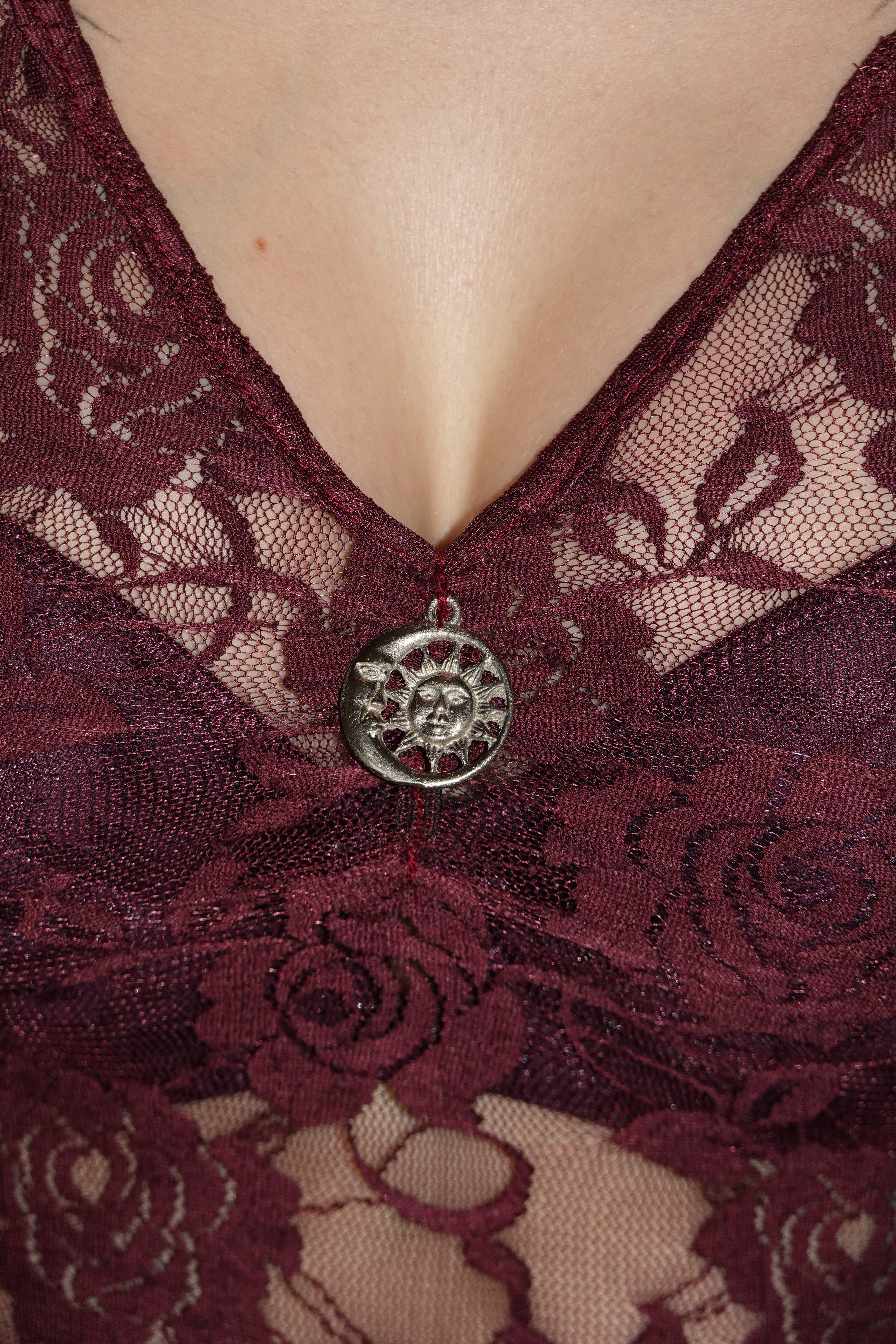 closeup Detail show of purple lacy dress with finished v-neckline, showcasing stainless steel moon-sun charm inspired by 90's whimsygoth. On model - Cascadia (Purple) dress - FM2U Clothing Australia | Gothic Alternative Whimsical Ethical Fashion witchy detailing moon and sun
