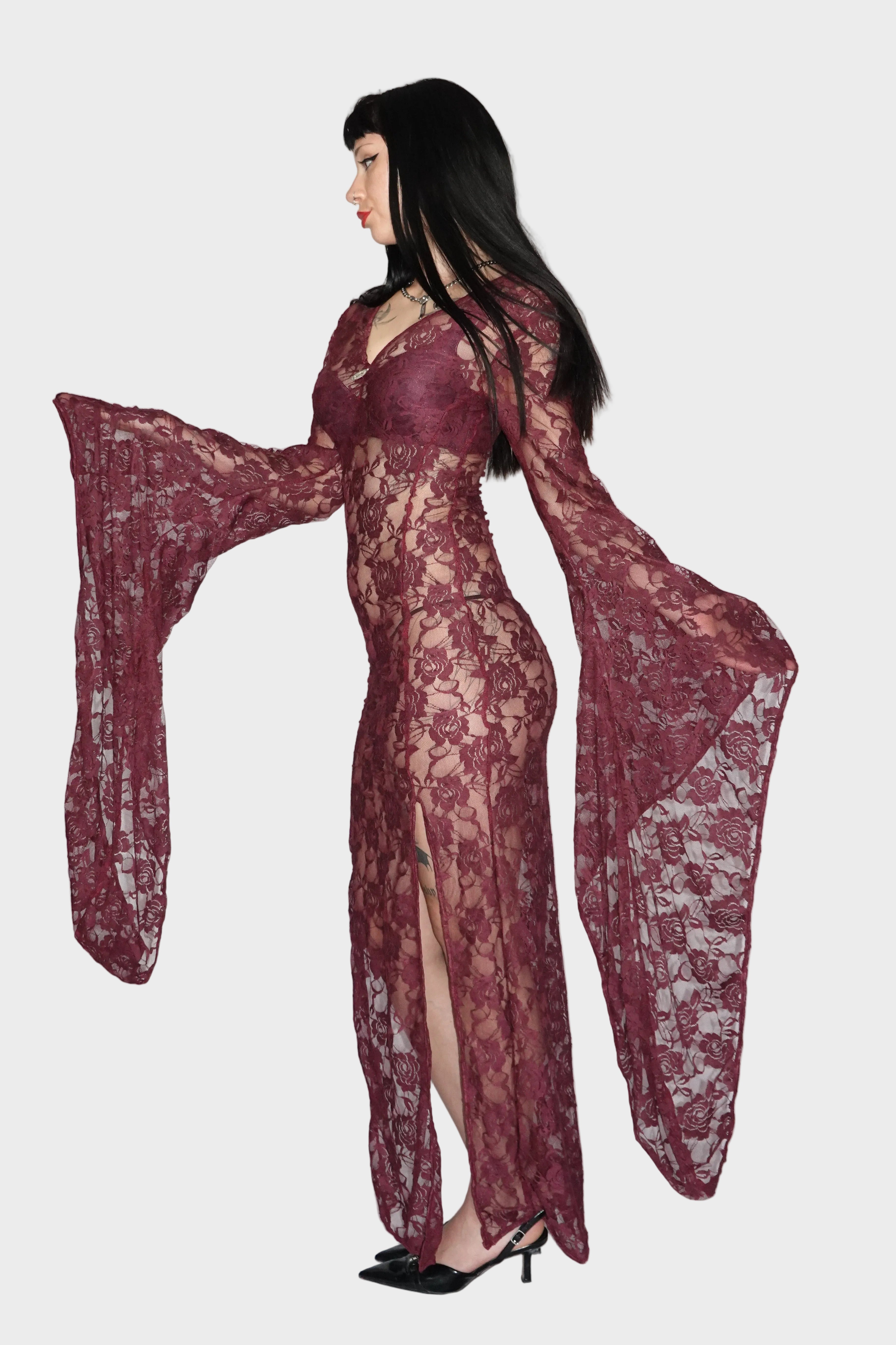 Side view of purple, sheer rose-patterned lace maxi dress showcasing flared drop sleeves and dual leg slits. On model - Cascadia (Purple) dress - FM2U Clothing Australia | Gothic Alternative Whimsical Ethical Fashion