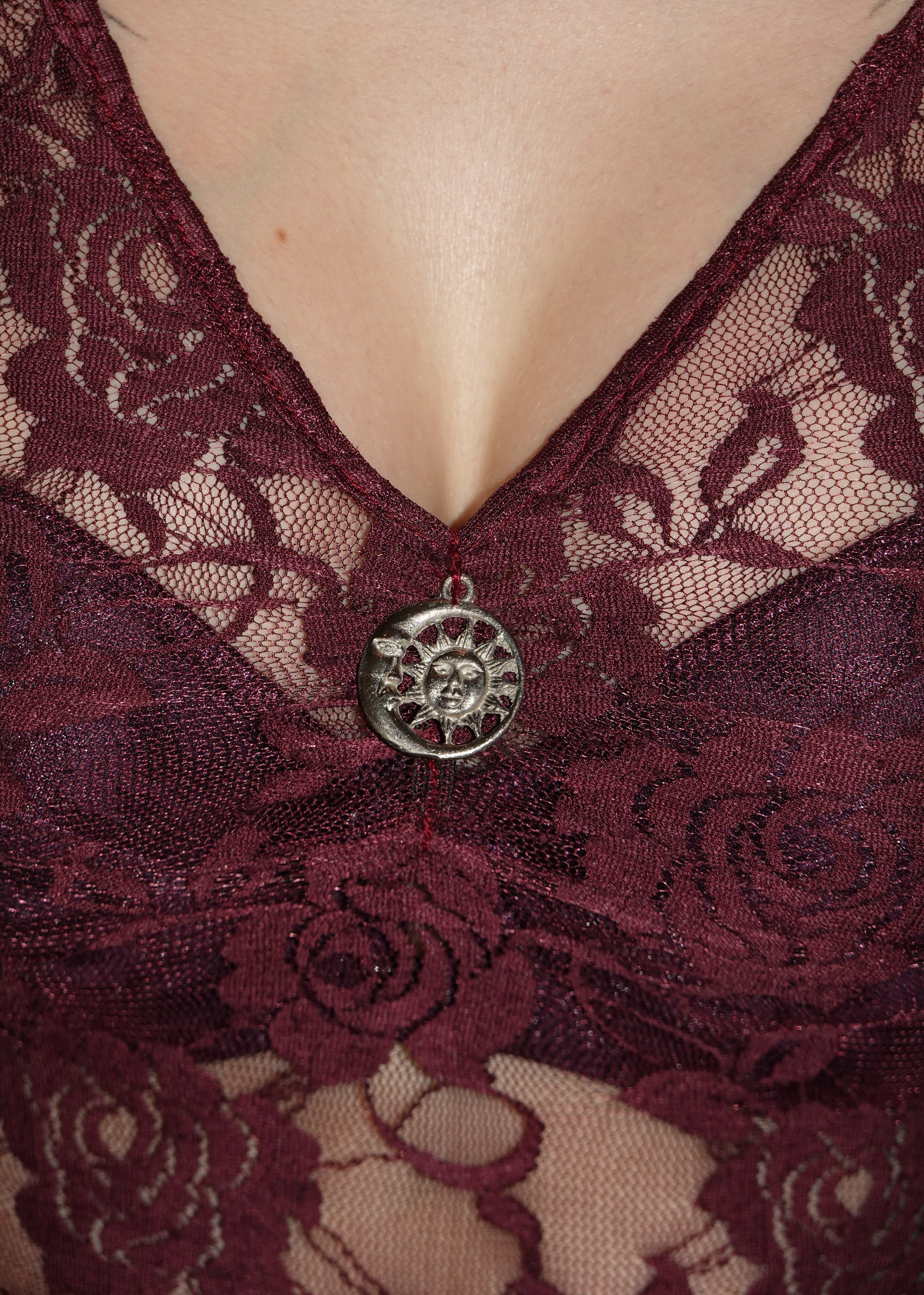 closeup Detail show of purple lacy dress with finished v-neckline, showcasing stainless steel moon-sun charm inspired by 90's whimsygoth. On model - Cascadia (Purple) dress - FM2U Clothing Australia | Gothic Alternative Whimsical Ethical Fashion witchy detailing moon and sun